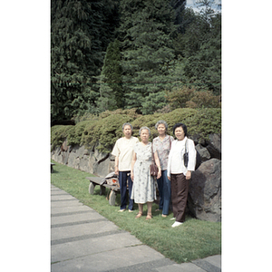 Four women stand against a stone wall in an unknown park