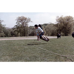 Association members jump across a rope while competing in a sack race