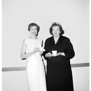 Two Faculty Wives Club members pose together holding teacups