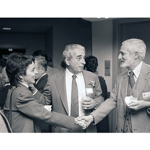 Attendees shaking hands at the Kariotis Hall dedication while George Kariotis looks on