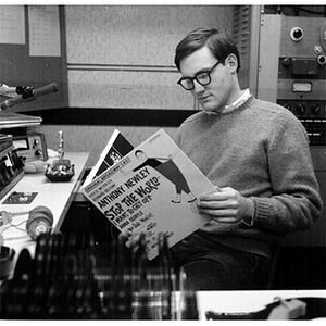 Young man looking at the album of the musical "Stop the World - I Want to Get Off" in the broadcast booth of the WNEU studio