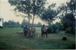 Charlie Hill and unidentified man (r. to l.), seated on a lawn