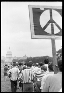 Line of marchers heading toward U.S. Capitol Building, one carrying a large sign with a peace symbol