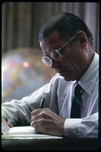 Defense Secretary Robert S. McNamara, working at his desk, pen in hand