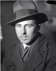 Arthur Hansen, photojournalist: close-up portrait wearing a fedora and trench coat
