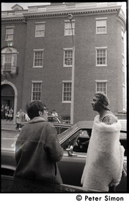 Umoja (Black student union) activist standing by car, wrapped in a sheepskin and talking to a white onlooker, at site of occupied administration building, Boston University