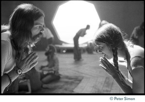 Man and woman, clasping hands, bow to one another, inside the dome at the Lama Foundation