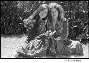 Dolma (left) and Usha (Cathy Brown): full-length portrait, seated on the ground, arms around one another