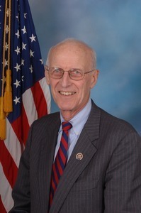 Congressman John W. Olver: half-length studio portrait in front of an American flag