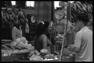 Woman behind the counter at a market stall selling produce in the old marketplace, Belize City