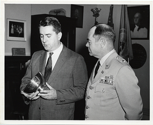 An unidentified man and unidentified U.S. military officer holding a ceremonial bowl