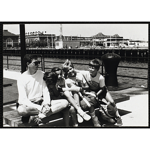 A Group of children smiling and sitting on a bench next to their counselor