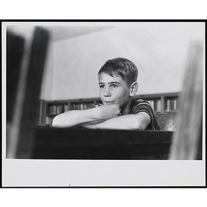 A Young boy looks on while sitting at a table