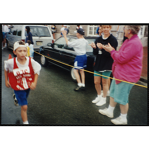 A boy runs past cheering spectators during the Battle of Bunker Hill Road Race