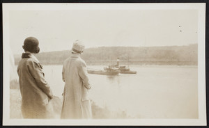 Two spectators watch as two barges sail down the Cape Cod Canal