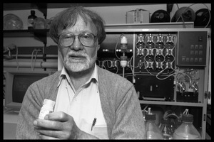 Louis Carpino standing in front of lab equipment, bottle in hand
