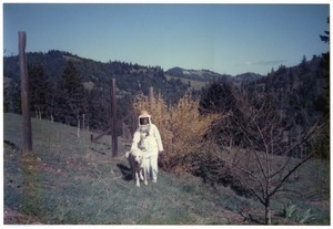 Sandi Sommer in beekeeping suit, with Maya the dog