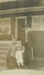 John Francis Lyman, wife and Eloise Caldwell Lyman standing in front of a house