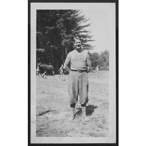 Man standing and posing in field in front of trees