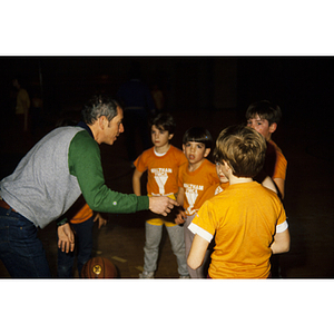 Man on basketball court instructing young boys wearing Waltham YMCA shirts