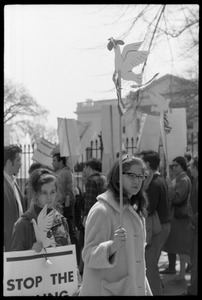 Woman holding a cutout cardboard peace dove on a stick, marching with antiwar demonstrators standing in front of the White House during the March on Washington