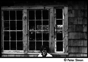 Laurie Dodge standing outside a house window, Packer Corners commune