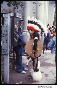 MUSE concert and rally: man in Native American ceremonial dress talking on a payphone