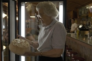 Waitress removing a cake from the pastry display, Miss Florence Diner