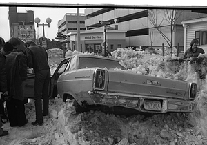 Pedestrians in front of car buried in snow on Cambridge Street