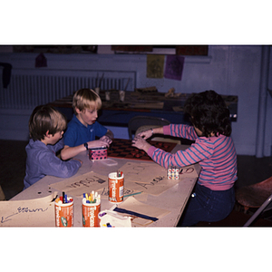 Young children sitting at a table doing art projects