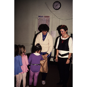 Young children lined up picking objects out of a bag