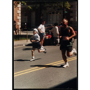A boy runs alongside a man during the Battle of Bunker Hill Road Race