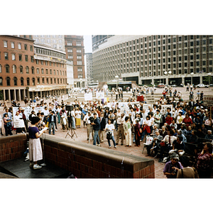 Crowd of protesters and concerned citizens listen to a Chinese woman speak at a rally for Long Guang Huang in City Hall Plaza in Boston