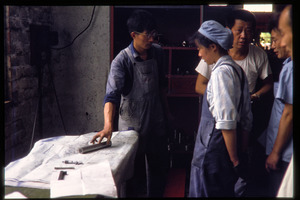 Shanghai tractor building factory: workers in discussion by set of blueprints