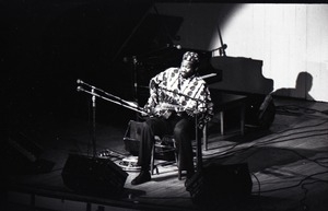 Taj Mahal in concert at Northfield, Mass.: Taj Mahal seated, playing steel guitar