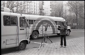 Richard Safft reading copy of Free Spirit Press, standing by camera and Free Spirit Press bus, during interview by Channel 5 news