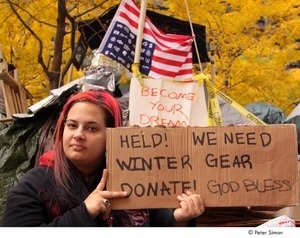 Occupy Wall Street: demonstrator holding cardboard sign reading, 'help! we need winter gear, donate, God bless'