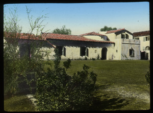 Spanish colonial building with red tile roof and lawn