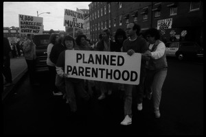 Planned Parenthood escorts with banner passing pro-life protesters in front of the Providence Planned Parenthood clinic