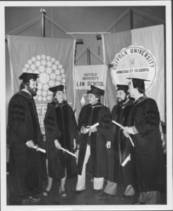 Five graduates hold their degrees under Suffolk banners at the 1980 Suffolk University commencement