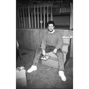 Unidentified man in jeans sits on the steps in a basement.