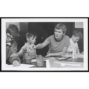 An art instructor helps a boy with a painting while two others work on their projects at the Charlestown Boys' Club