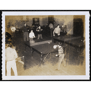 Two plays table tennis as a man looks on