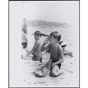 Two boys enjoy lunch on a beach