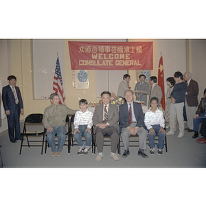 Henry Wong sits with two men and two boys at a welcome party for the Consulate General of the People's Republic of Consulate in Boston