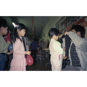 Young girl watches as the girl in front of her has a blindfold put on to play "pin the tail on the donkey"