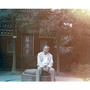 Association member sits on a rock in a Chinese garden