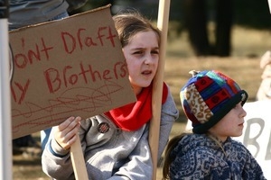 Young protesters in the crowd holding a sign 'Do'nt draft my brothers': rally and march against the Iraq War