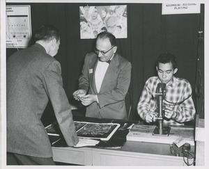 A staff member and trainee at a jewelry making display table