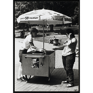 A teenage boy operating an ice juice cart serves a woman on Boston Common